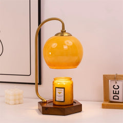 Retro candle warmer lamp with amber glass shade and candle on a desk