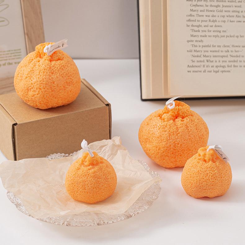 A variety of ugly tangerine candles in different sizes displayed beside a box