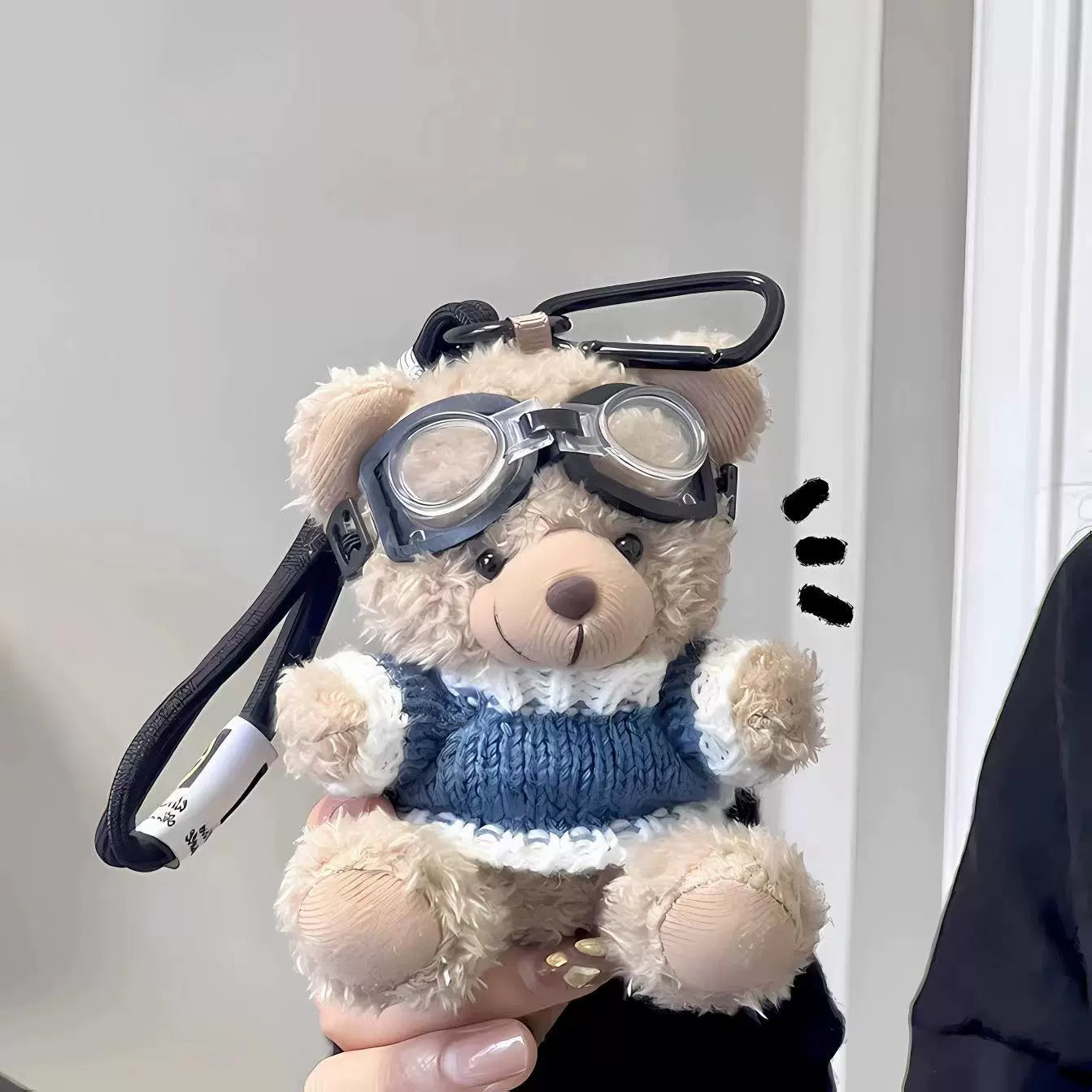 Aviator bear plush keychain in blue and white sweater and goggles, hand-held on plain background