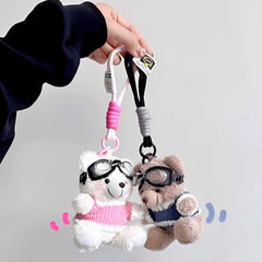 Pair of aviator bear plush keychains in pink and blue sweaters, suspended by pastel cords