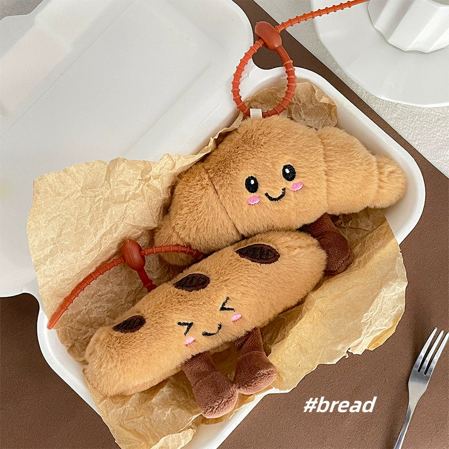 Croissant and baguette plush keychains nestled together in a takeout box
