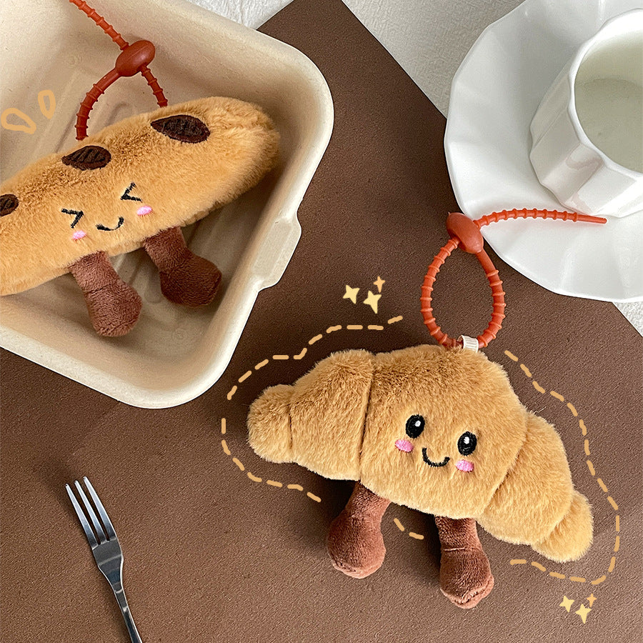 Bread-shaped plush keychains in a box with illustrated stars around them