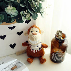 Cute brown monkey plush toy with a toothy smile, next to a brown vase under a leafy plant