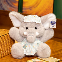 Bruce Comfort Sitting Elephant Plush Toy with blue bonnet resting on a wooden table, inviting gentle moments.