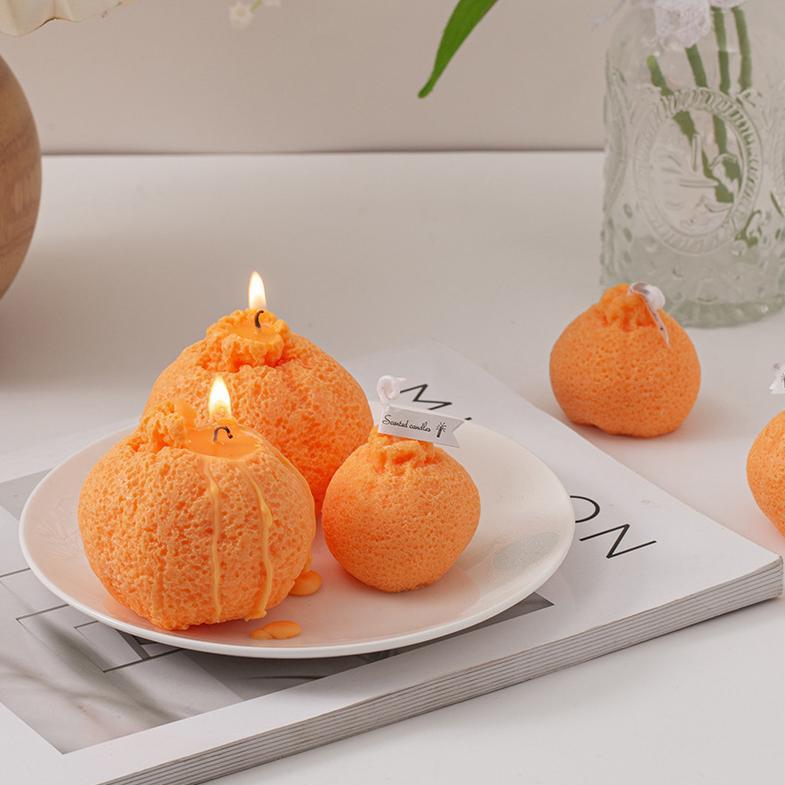 Two burning ugly tangerine candles and smaller ones displayed on a white plate