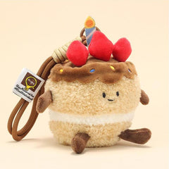 Side view of cake plush keychain with smiling face, strawberries, and candle