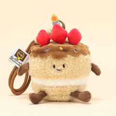 Side view of cake plush keychain with smiling face, strawberries, and candle