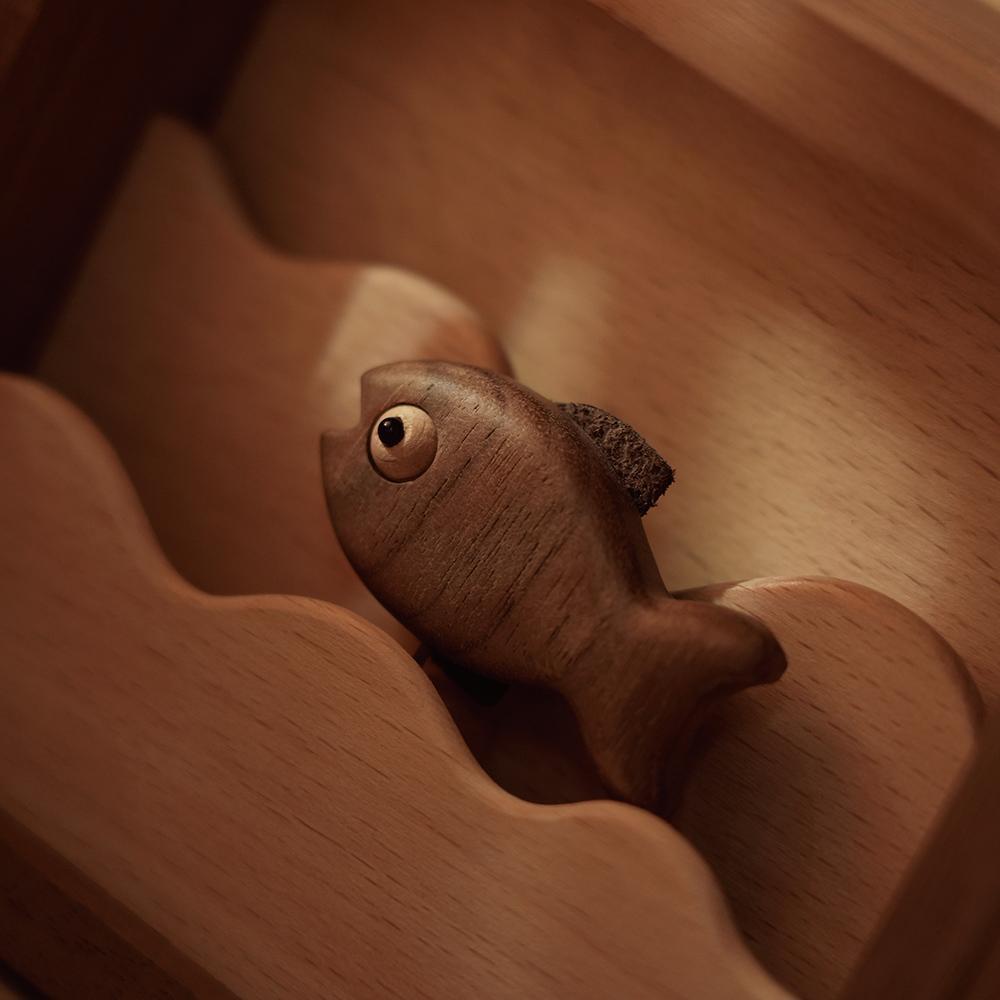 Close-up detail of the movable handcrafted wooden fish set inside the night light, highlighting artisanal craftsmanship and fine wood texture.