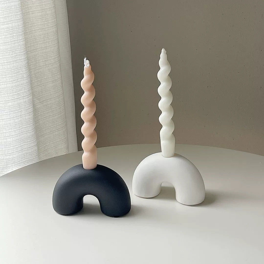 Two creative half arch ceramic candle holders in black and white with spiral candles, elegantly arranged on a minimal white table