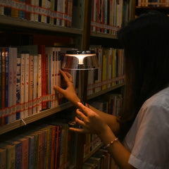 The Creative Modern Desk Lamp illuminating a cozy reading scene in a library, exemplifying its mood-enhancing features.
