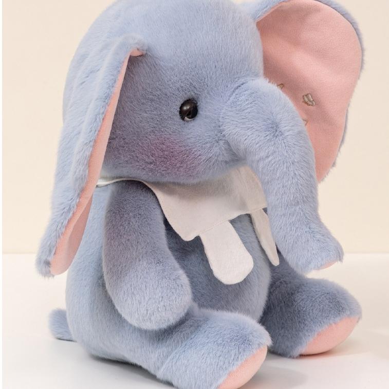 Side profile of the elephant plush toy displaying long trunk and embroidered ear details