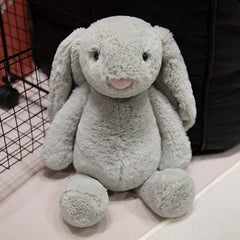 Gray lop-eared bunny plush toy sitting calmly, inviting connection and gentle touch.