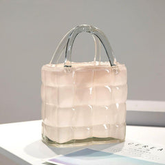 Close-up of softly colored handbag-style glass vase with elegant handle