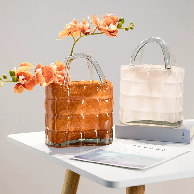 Elegant handbag glass vases in white and amber displayed together with fresh orange orchids