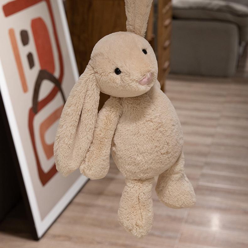 Beige lop-eared bunny plush toy hanging in the air, expressing lighthearted joy and freedom.