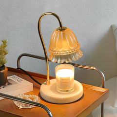Delicate candle warmer lamp with floral design on a bedside table, softly casting light with a white scented candle