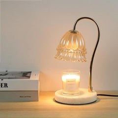 Elegant candle warmer lamp with lily of the valley glass shade and white marble base, softly illuminating a candle on a desk