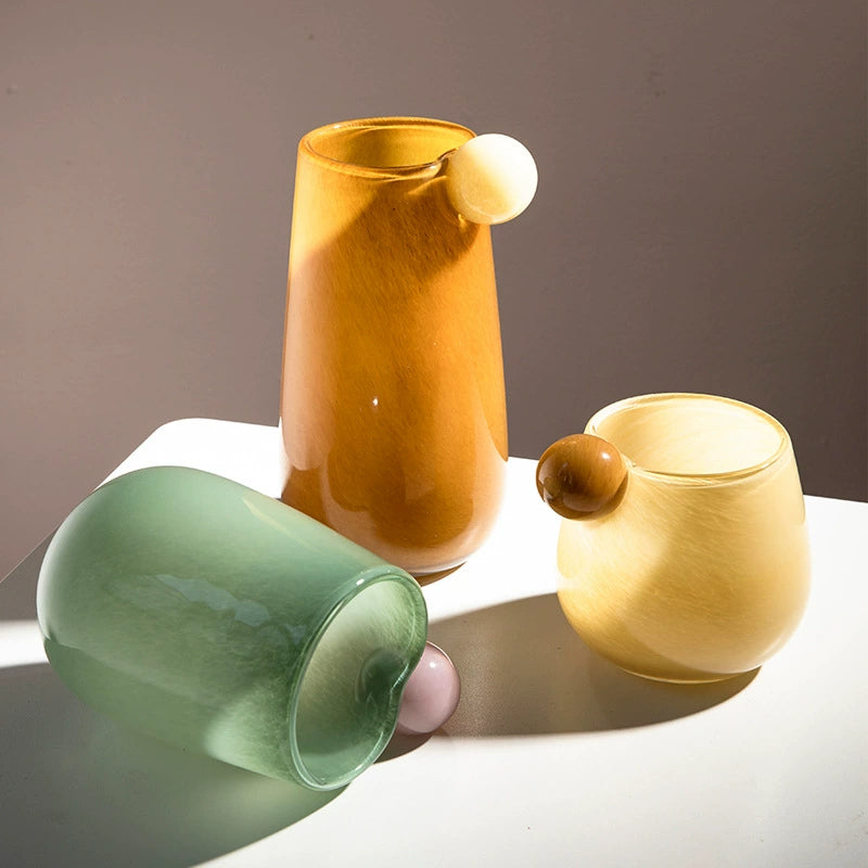 Amber, yellow, and green candy glass vases arranged elegantly, highlighting their chic design and playful surface textures.