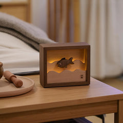 Handcrafted wooden fish night light casting gentle light on a cozy bedside table, enhancing relaxation and comfort.