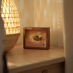 Wooden fish night light glowing softly beside a window with flowing curtains, adding warmth and a calm touch to the space.