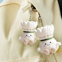 Two shuttlecock plush keychains hanging from a beige bag, each with a joyful expression.