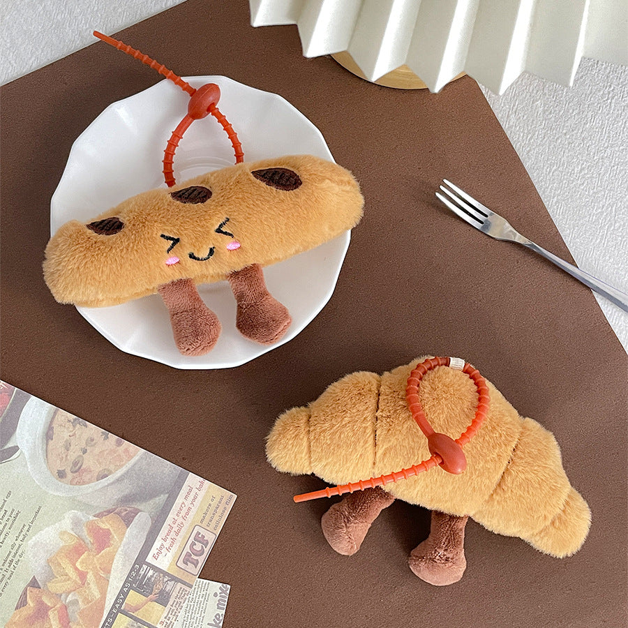 Croissant and baguette plush keychains arranged together on a plate