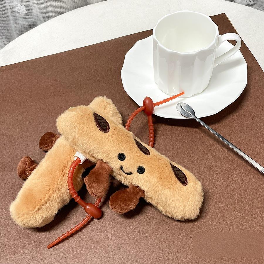 Two baguette plush keychains resting together near a cup and saucer