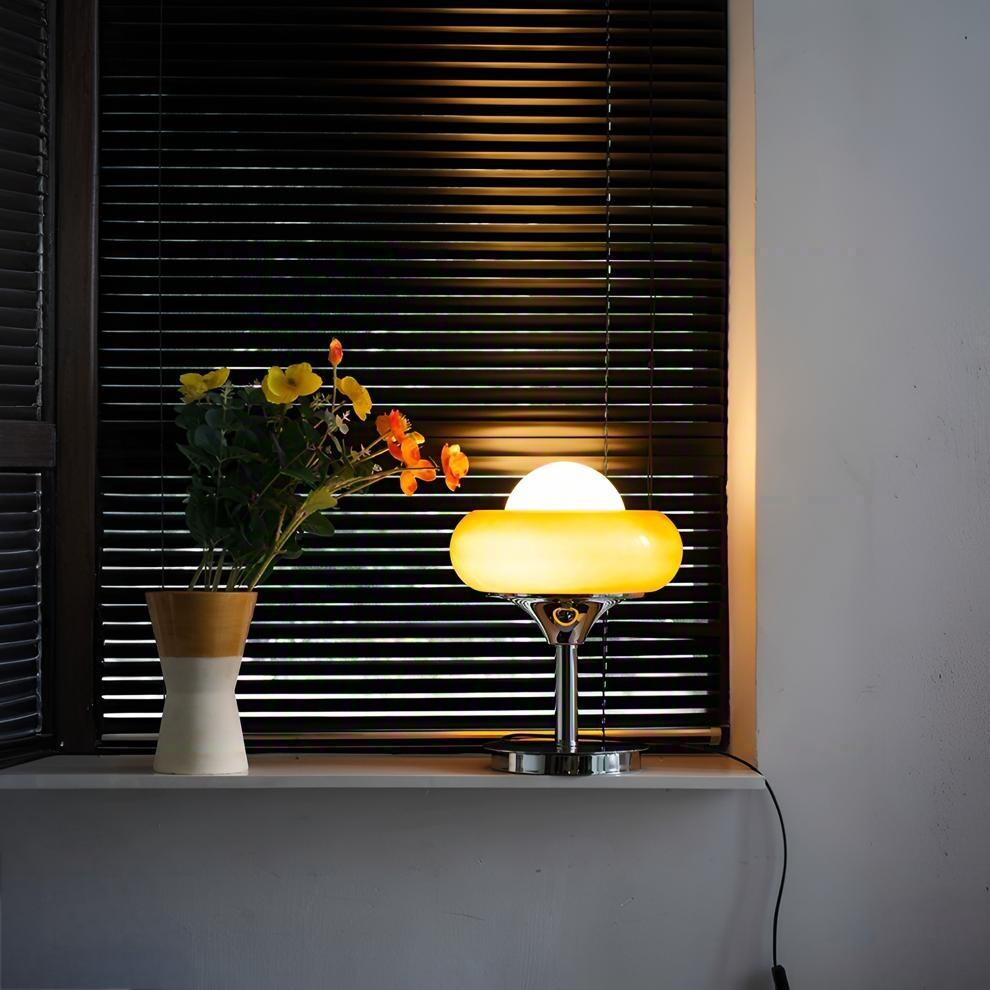Yellow retro desk lamp glowing warmly on windowsill, alongside floral decoration
