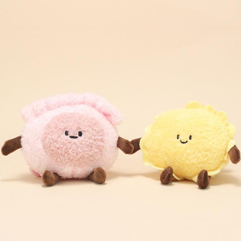 Pink shrimp dumpling and yellow tart plush keychains holding hands
