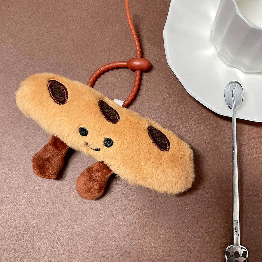 Smiling baguette plush keychain placed on a saucer next to a white cup