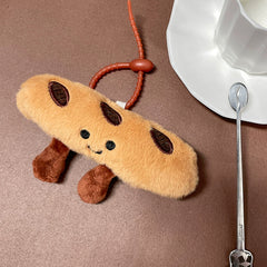 Smiling baguette plush keychain placed on a saucer next to a white cup