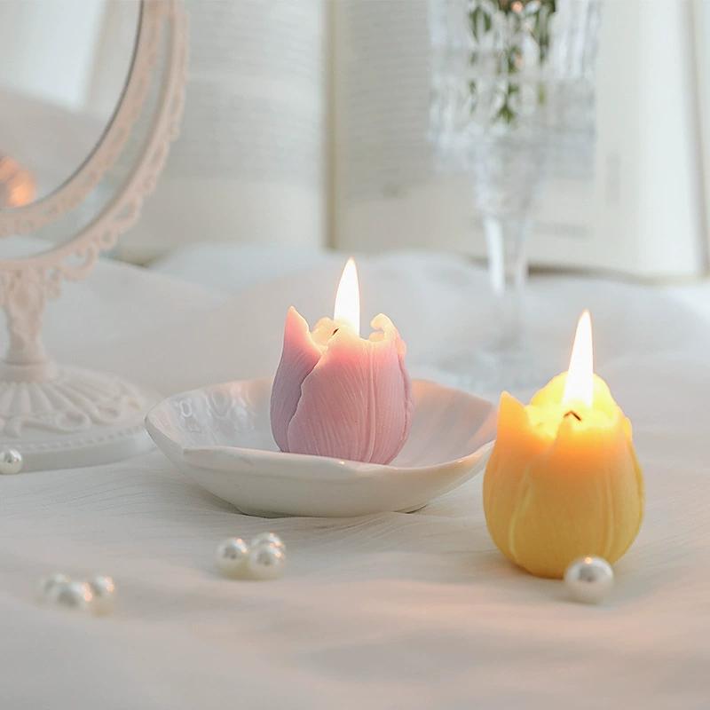 Two tulip candles of different colors burning gently in a cozy vanity setting.