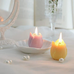Two tulip candles of different colors burning gently in a cozy vanity setting.
