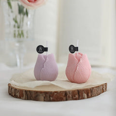 Pair of lilac and pink tulip candles elegantly arranged on a wooden tray with flowers.