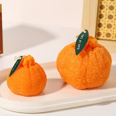Pair of ugly tangerine shaped candles with "East of Life" leaf tags displayed on a plate