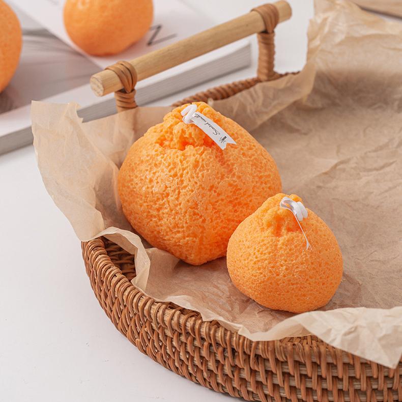 Two ugly tangerine candles resting in a rustic woven basket