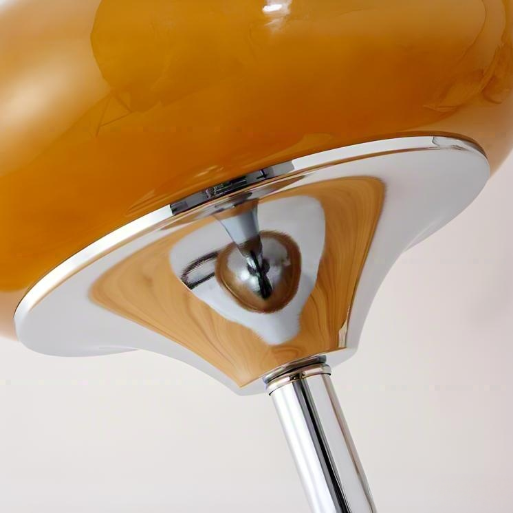 Close-up of chrome lamp base and retro yellow glass shade, reflecting refined craftsmanship