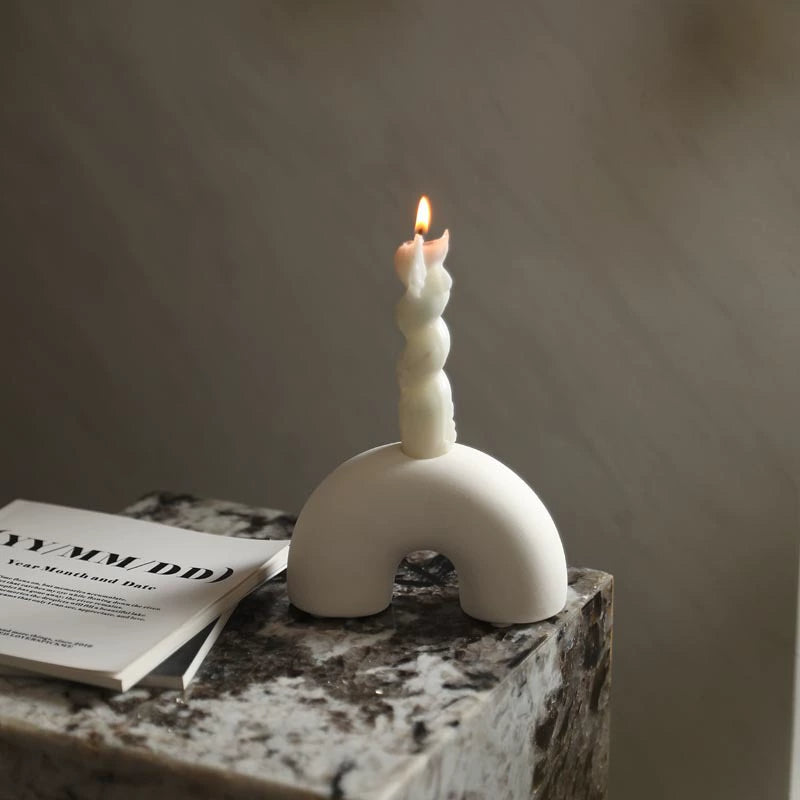 White half circle ceramic candle holder with a lit spiral candle on a marble side table, creating a cozy ambiance