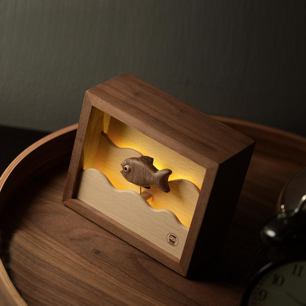 Artistic angled shot of the handcrafted wooden fish night light, showing the vibrant three-tone illumination and intricate woodwork.