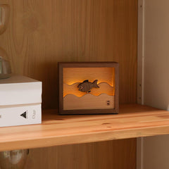 Charming wooden fish night light placed on a bookshelf, enriching the space with a decorative touch and emotional warmth.
