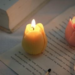 Glowing yellow tulip candle lit, creating a warm atmosphere on an open book.