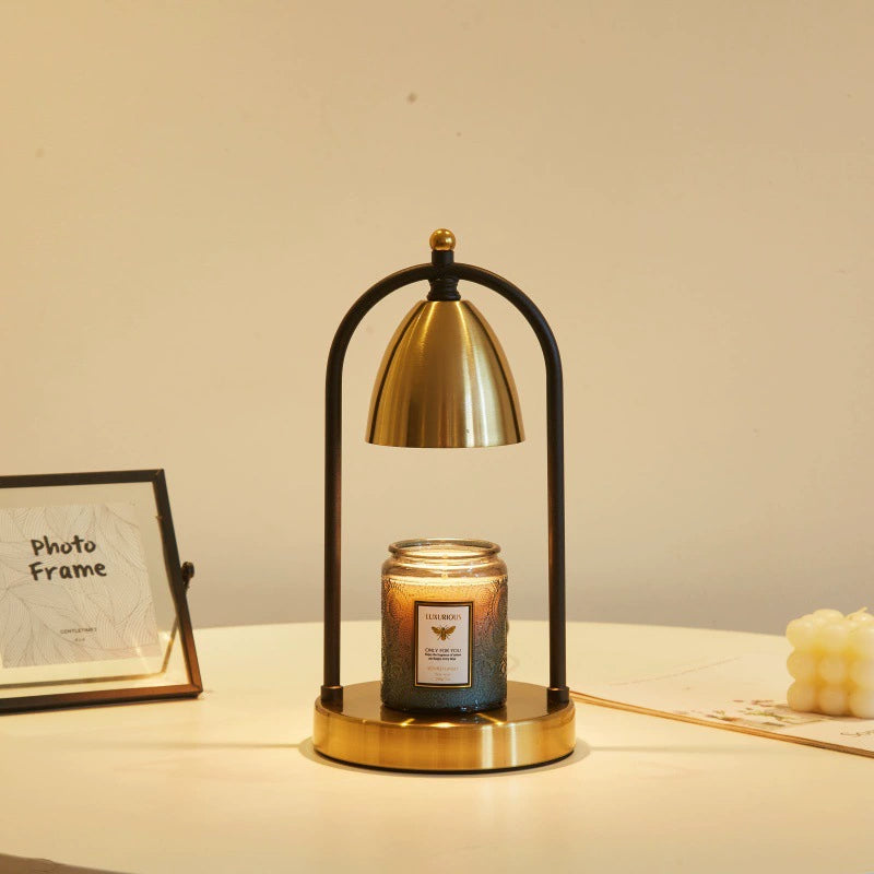 Black and gold candle warmer lamp placed next to a photo frame, embodying vintage charm on a stylish table.