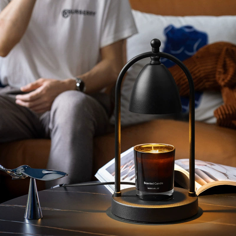 Black minimalist candle warmer lamp on a coffee table, radiating warmth in a stylish modern living room setting.