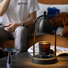 Black minimalist candle warmer lamp on a coffee table, radiating warmth in a stylish modern living room setting.