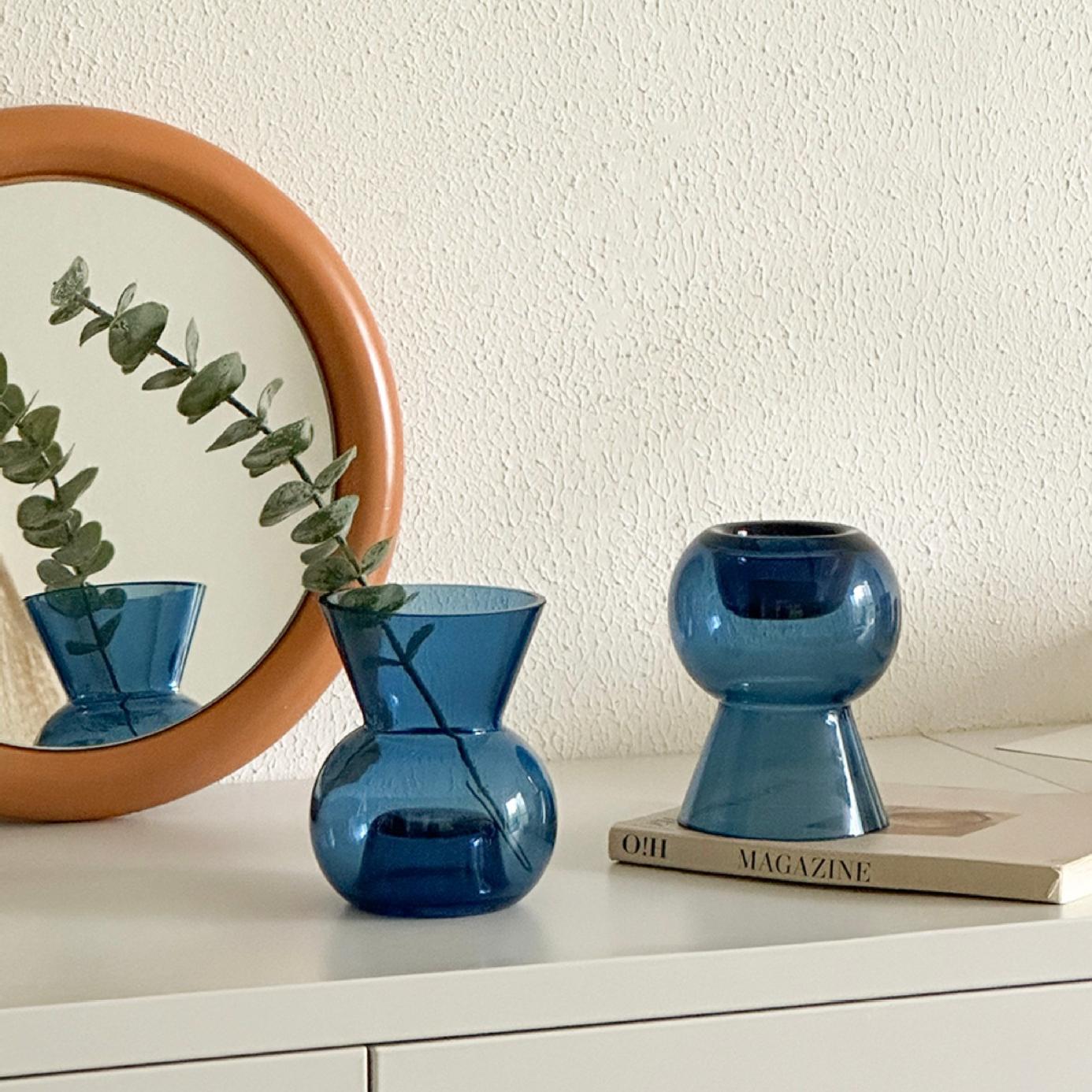 Blue glass candle holder paired with vase, creating a harmonious and peaceful home scene near a mirror.