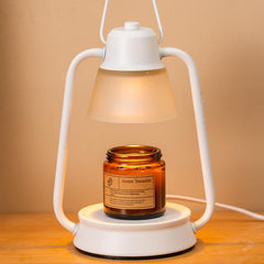 Cozy warm-lit white candle warmer lamp melting a brown scented candle for ambient mood