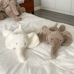 Light and dark elephant plush toys together on a white bed, symbolizing unity and emotional support.