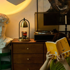 Gold vintage candle warmer lamp illuminating a candle on a stylish dresser, enhancing relaxing, artistic living room vibes.