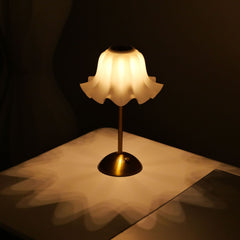 The minimalist desk lamp casting a beautiful, soft petal-like shadow on the surface below, creating a tranquil atmosphere with its warm illumination.
