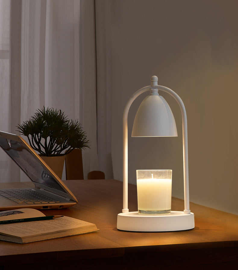 All-white minimalist candle warmer lamp elegantly lighting up a clear candle, perfect for serene work or study spaces.